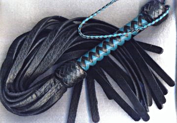 An aqua and black handled bison flogger with heavy tails.